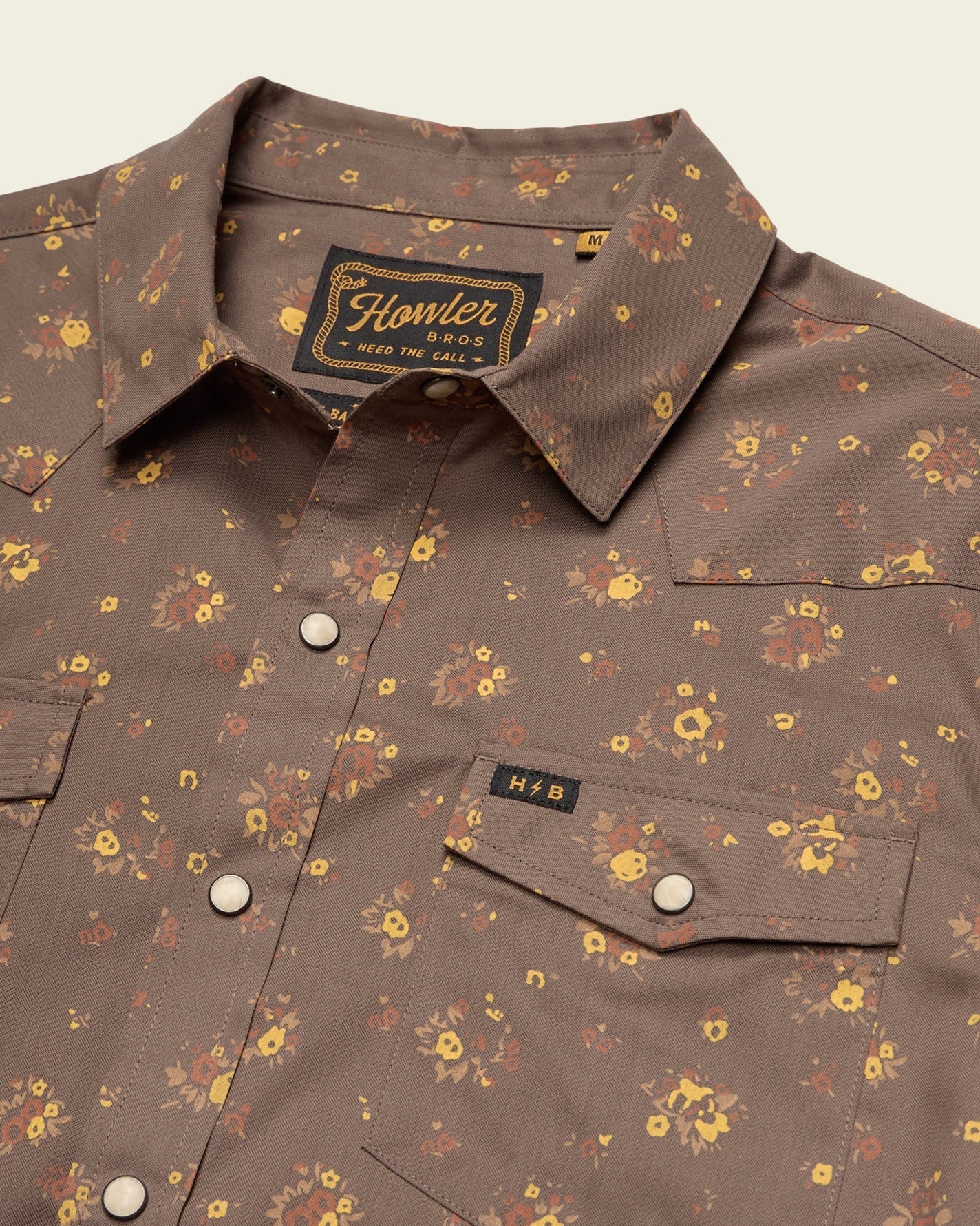 Brown floral patterned shirt with 'Howler' label on a beige background