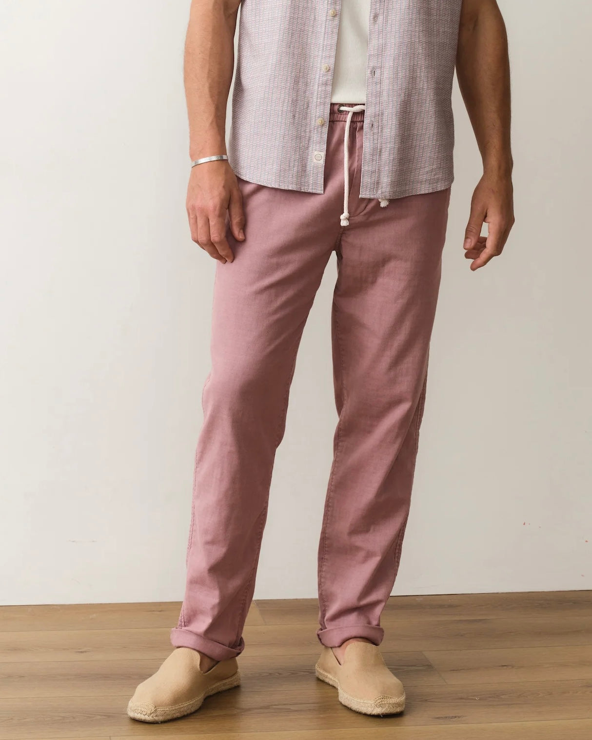 Person wearing pink pants and a light-colored shirt against a plain background