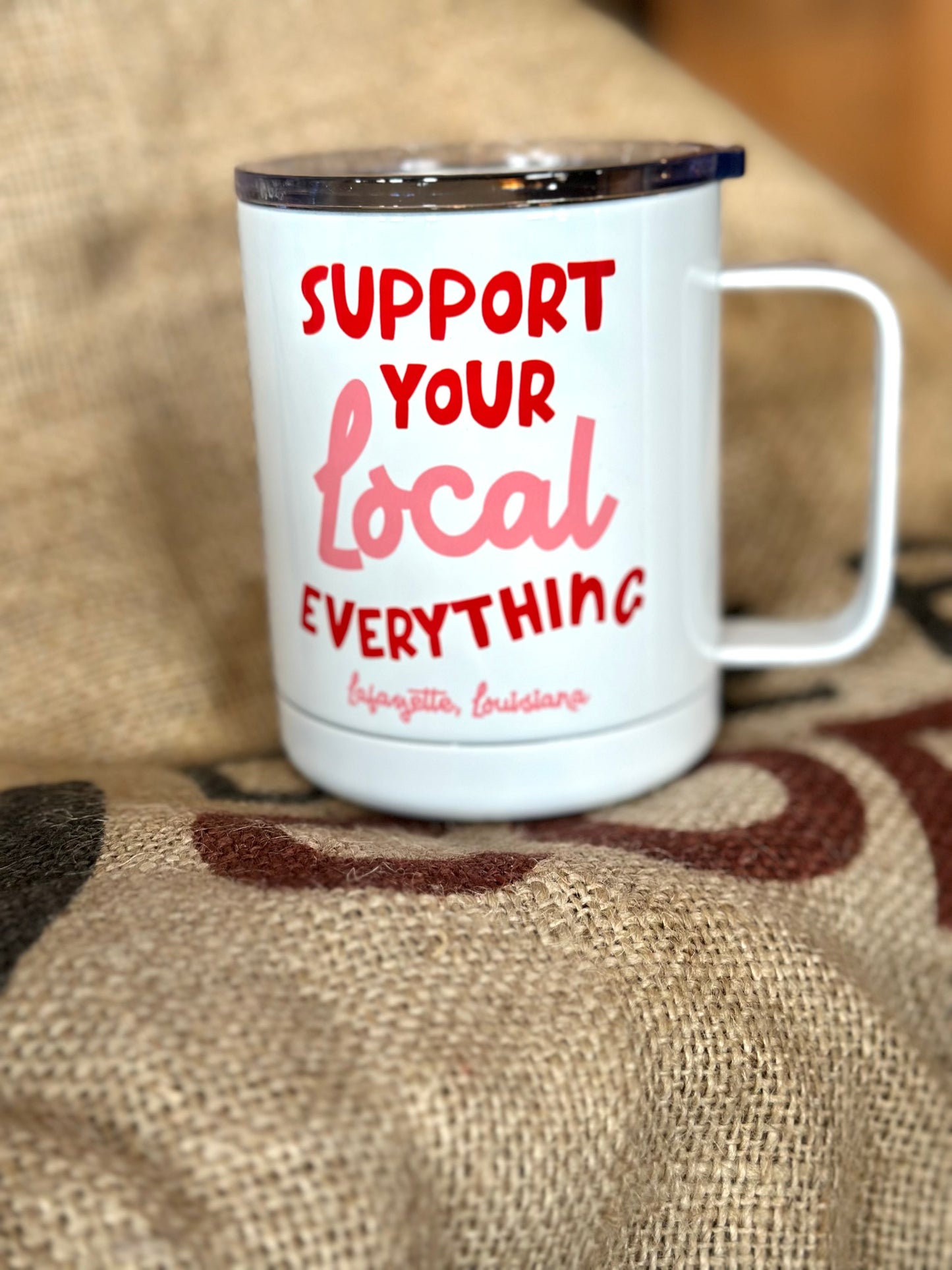 White mug with red and pink text on a textured surface