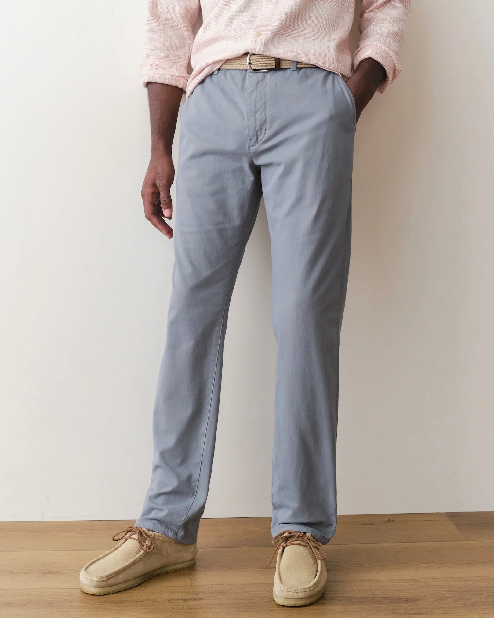 Person wearing light blue pants and beige shoes against a plain background