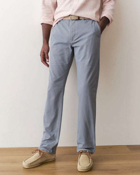 Person wearing light blue pants and beige shoes against a plain background