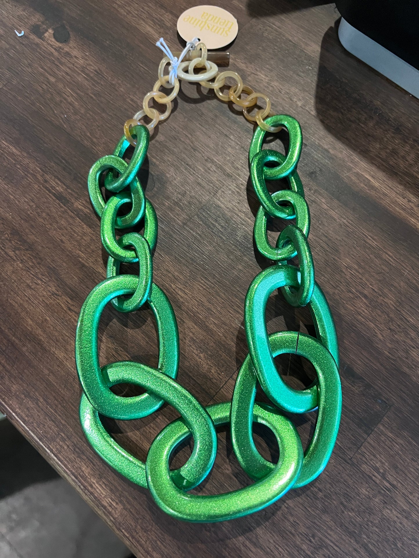 Green chain bracelet on a wooden surface