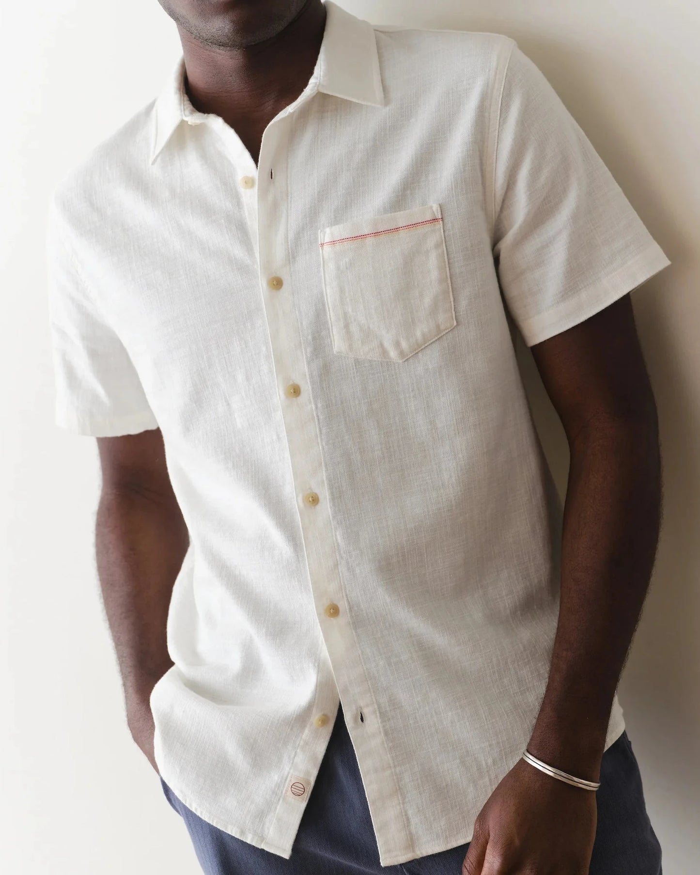 Man wearing a light-colored short-sleeve shirt against a plain background