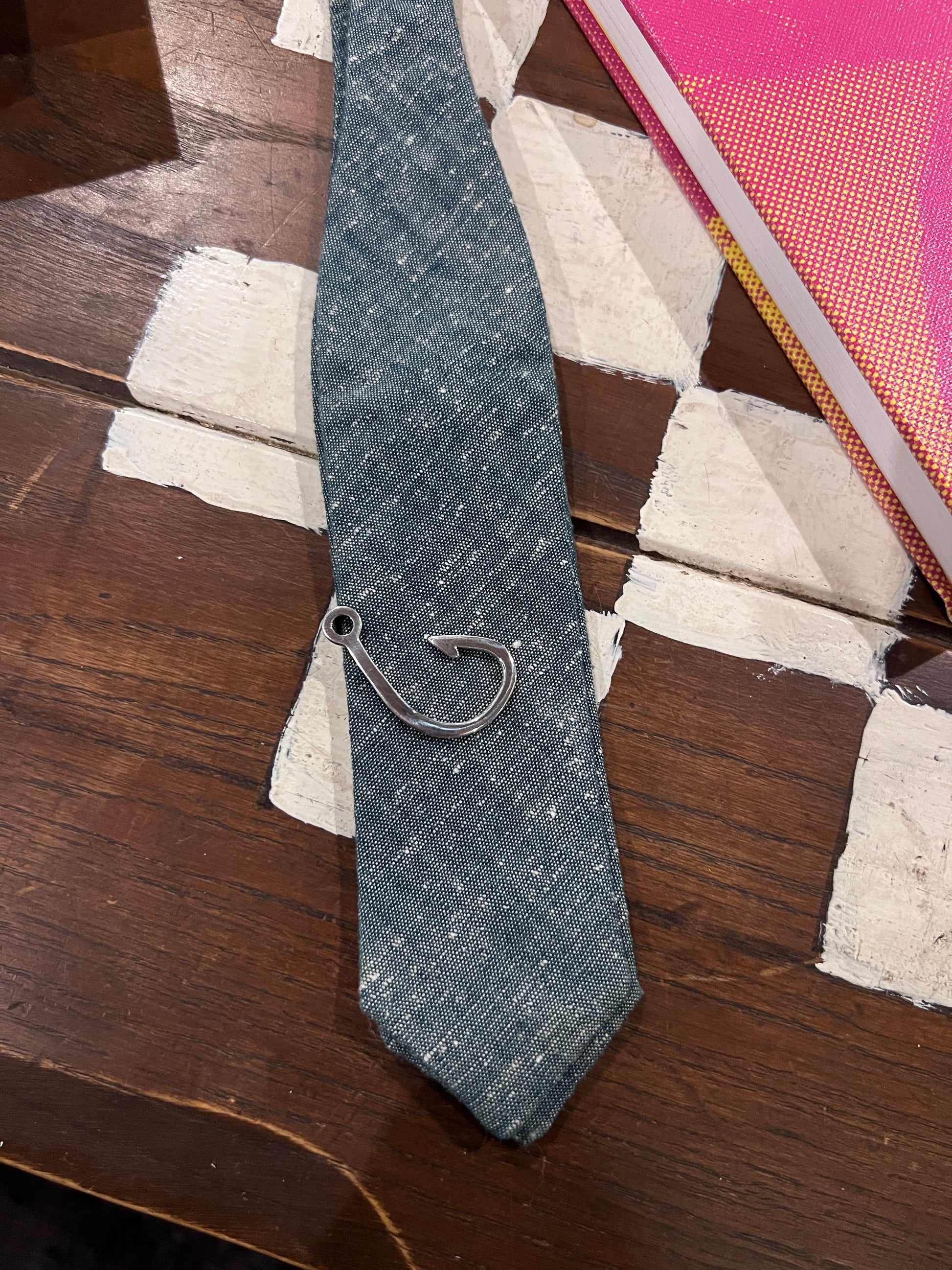Denim tie with a metal clasp on a wooden surface
