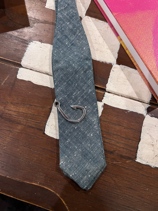 Denim tie with a metal clasp on a wooden surface