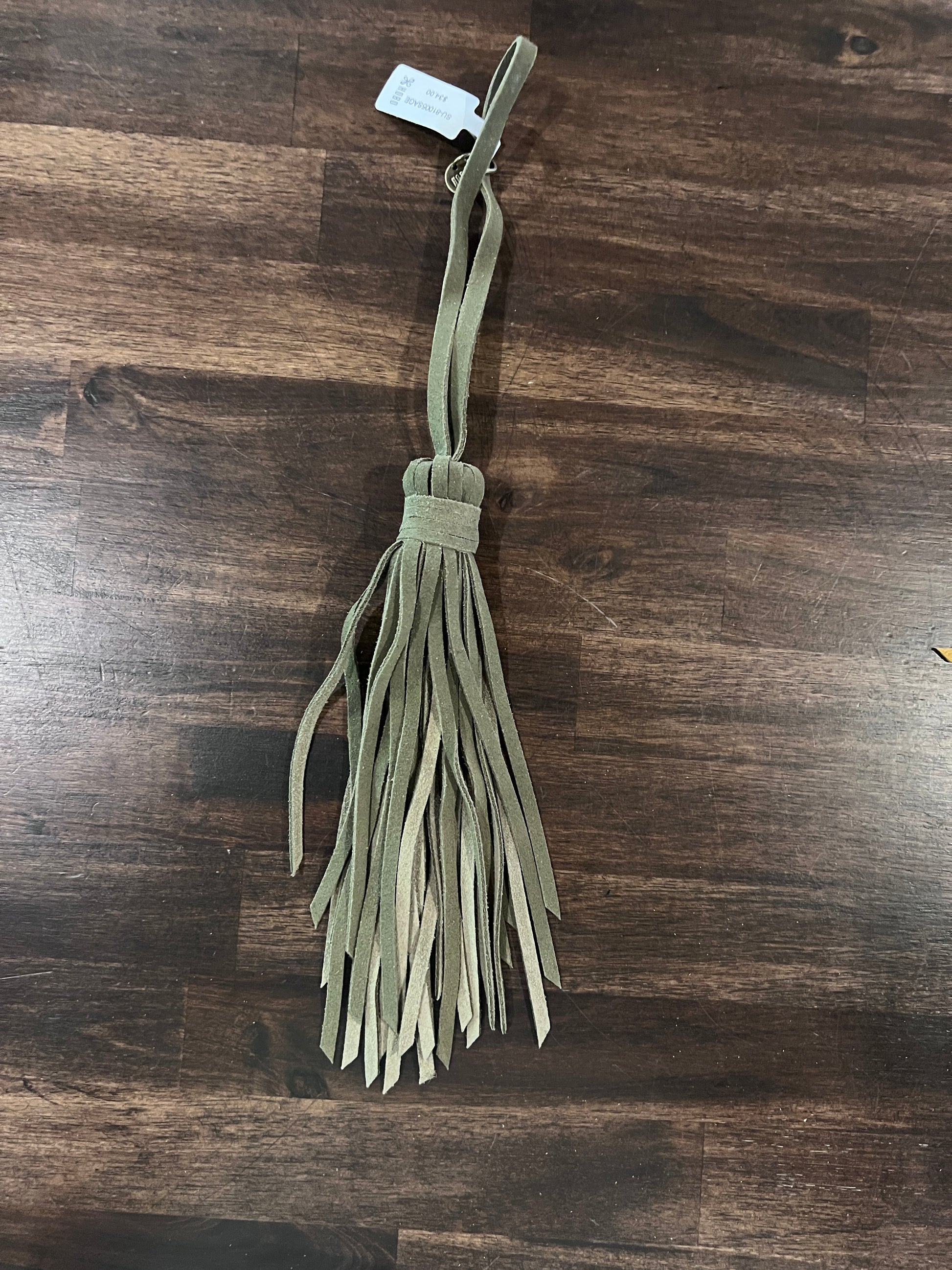 Green fabric tassel on a wooden surface