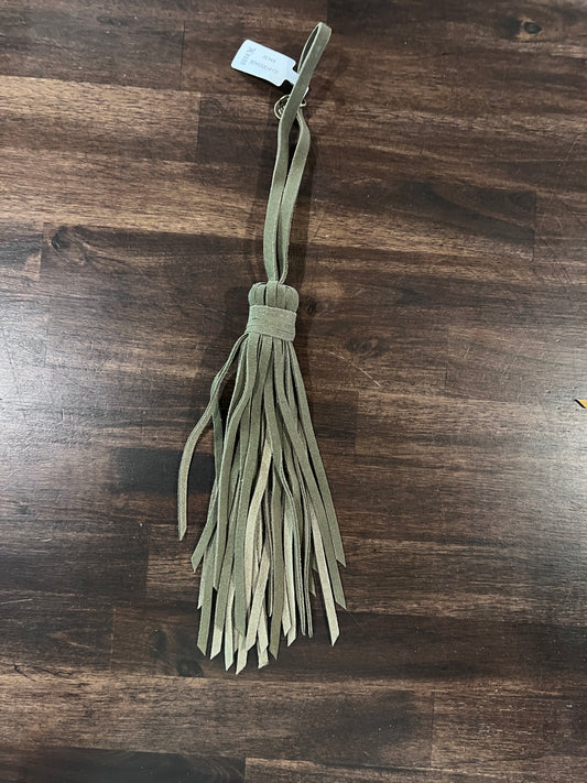 Green fabric tassel on a wooden surface