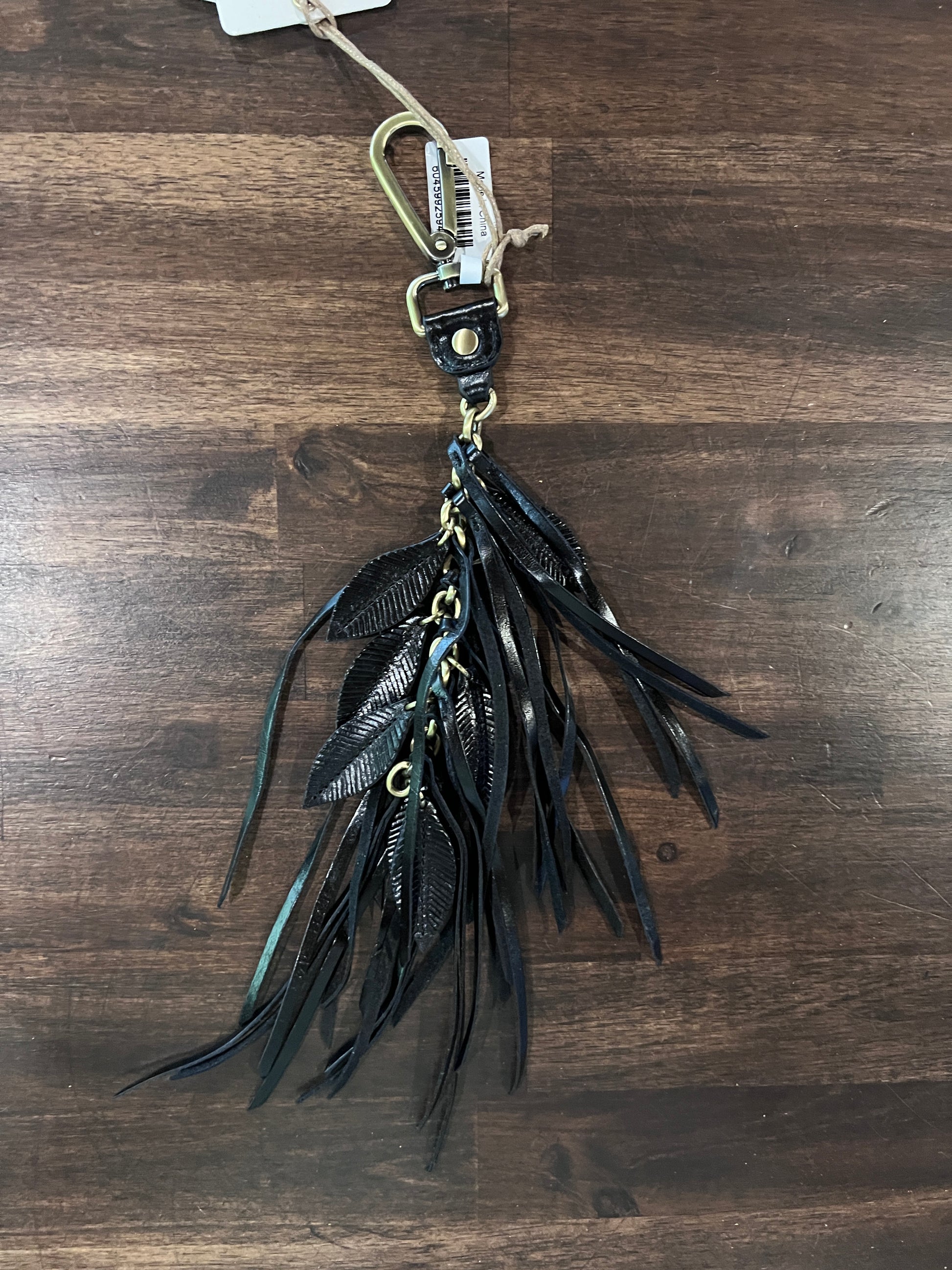Black feather keychain on a wooden surface