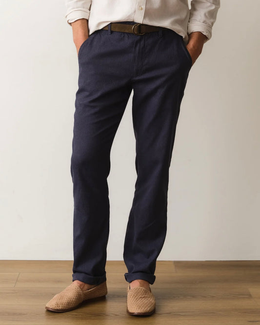 Person wearing navy pants and beige shoes on a plain background