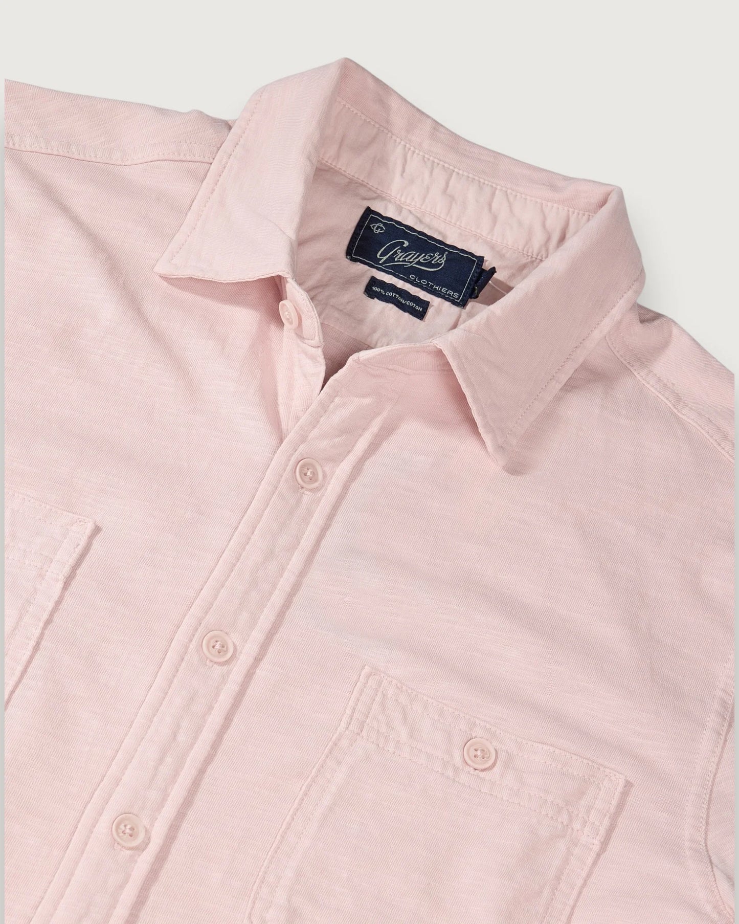 Pink shirt with a brand label on a light gray background
