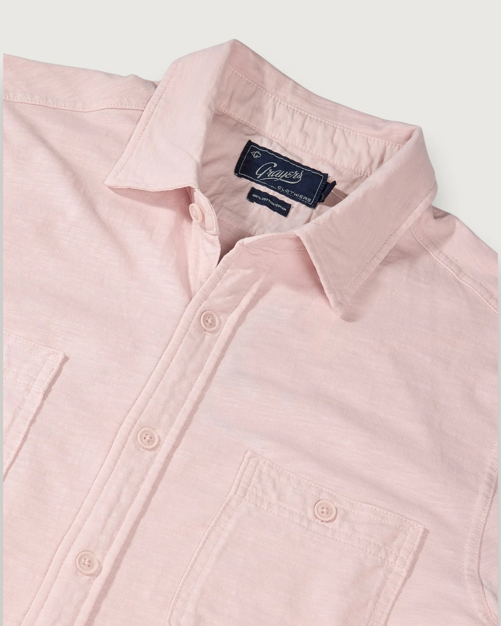 Pink shirt with a brand label on a light gray background