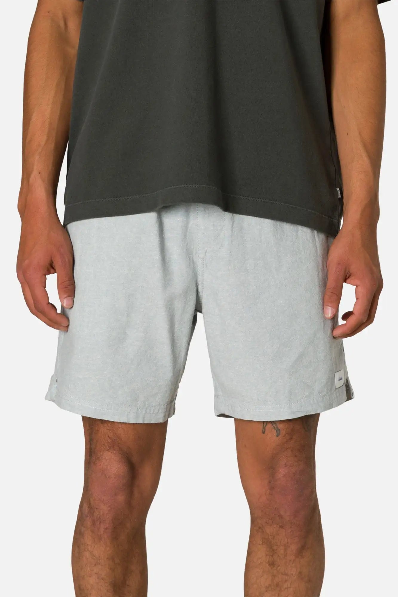 Person wearing gray shorts and a black sleeveless shirt on a white background