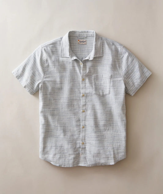 A short-sleeve button-up shirt with a subtle gray and white textured stripe pattern, laid flat against a solid beige background.