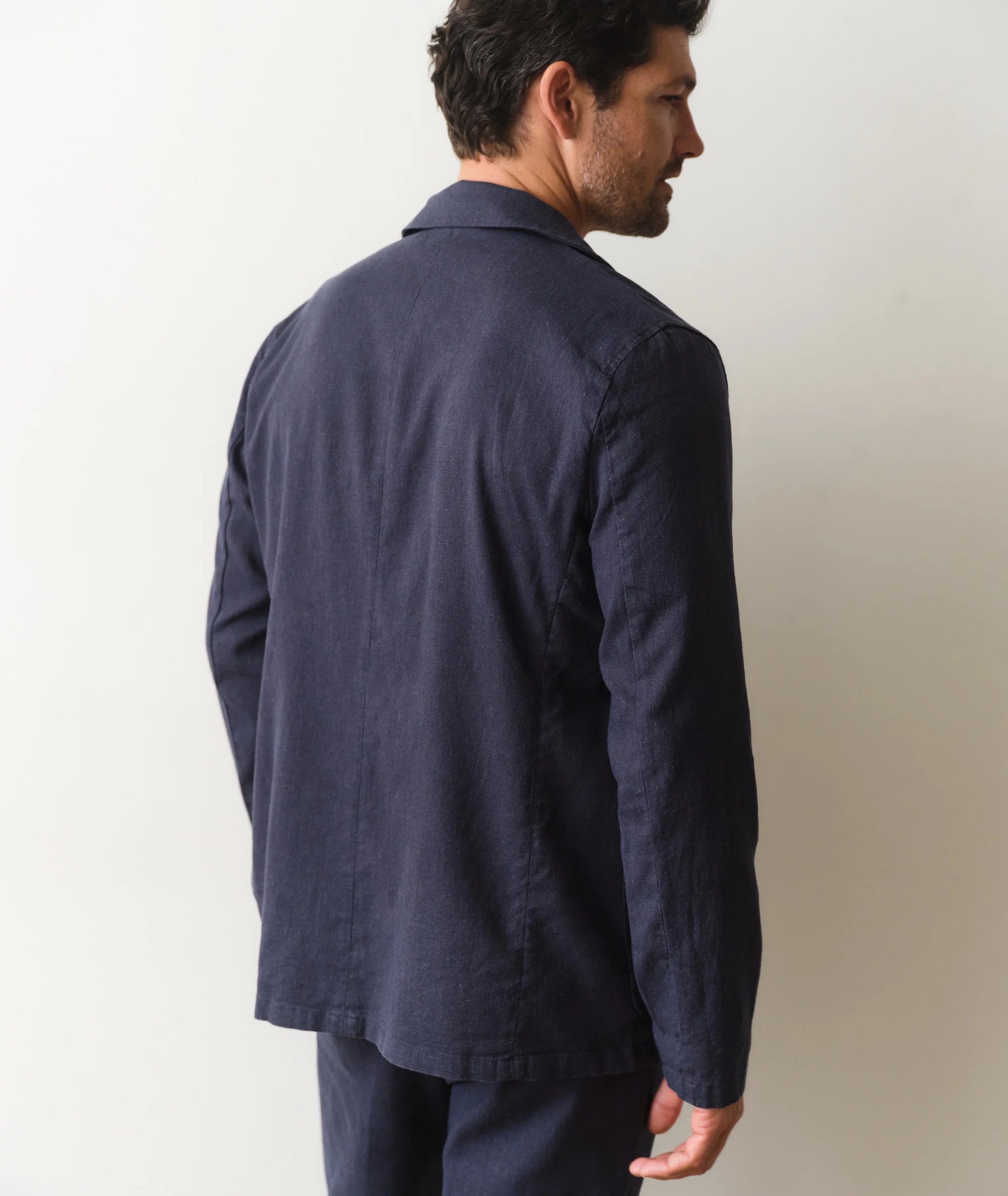 Man wearing a navy blue jacket and pants against a plain background