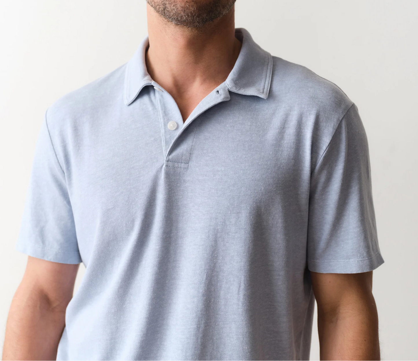 Man wearing a light blue polo shirt against a plain background
