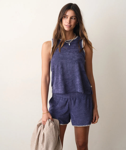 Woman wearing a blue sleeveless top and shorts set against a plain background
