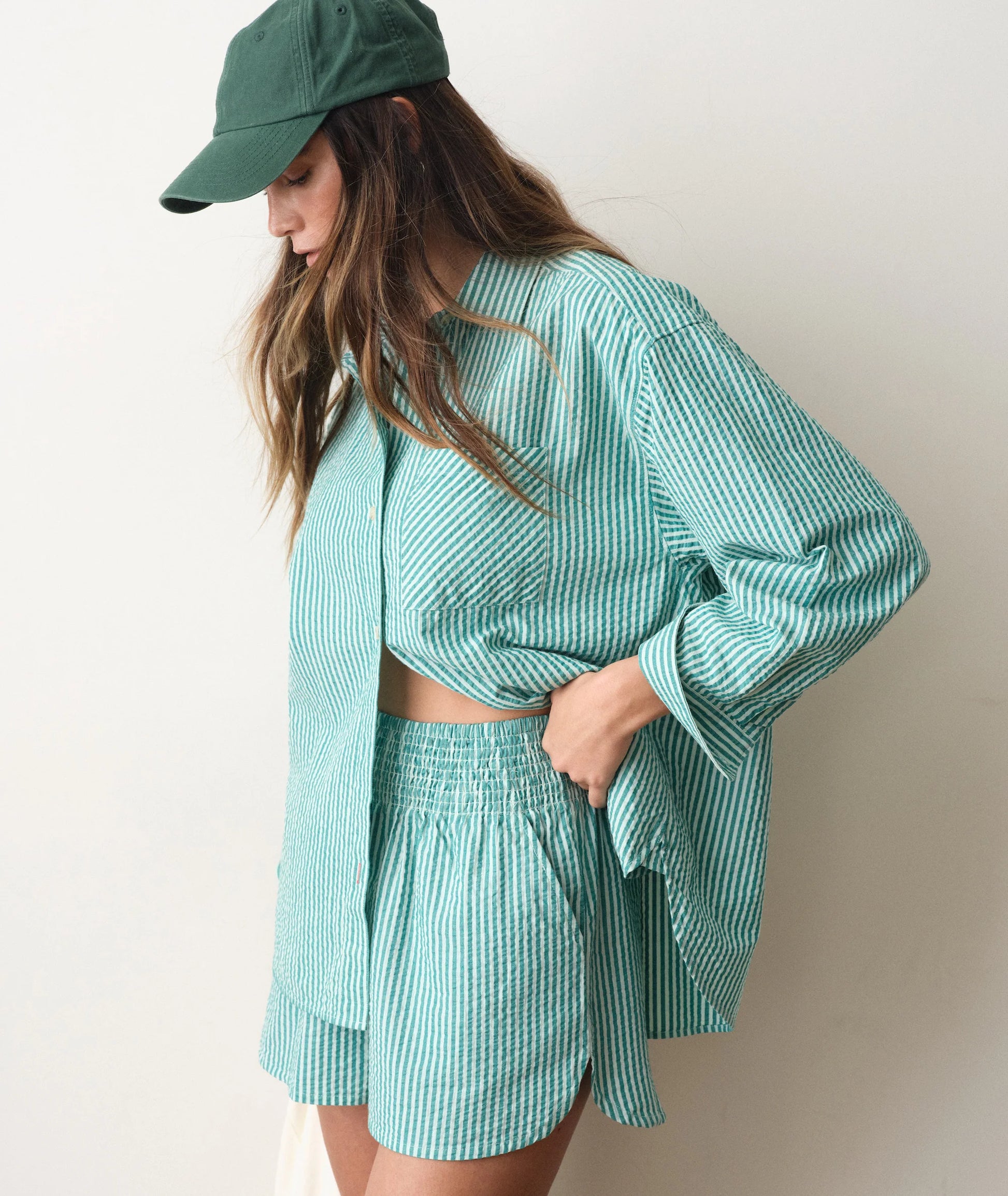 Woman wearing a green striped outfit with a matching cap against a plain background
