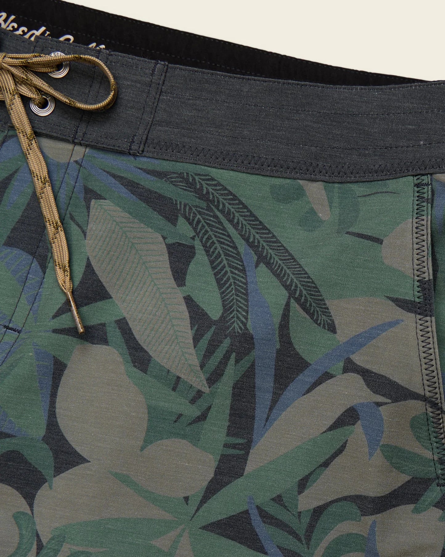 Tropical leaf patterned shorts with a close-up of the waistband and fabric texture.