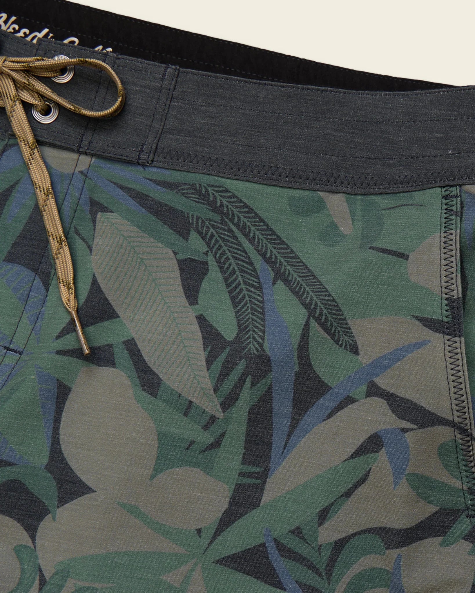 Tropical leaf patterned shorts with a close-up of the waistband and fabric texture.