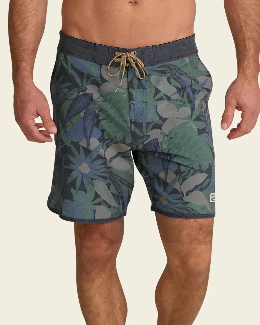 Man wearing green camouflage swim shorts on a beige background