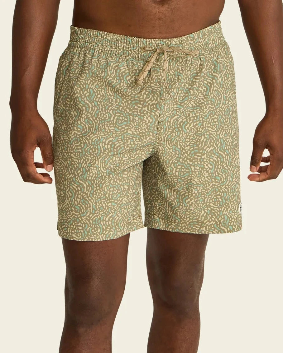 Person wearing green patterned shorts on a beige background
