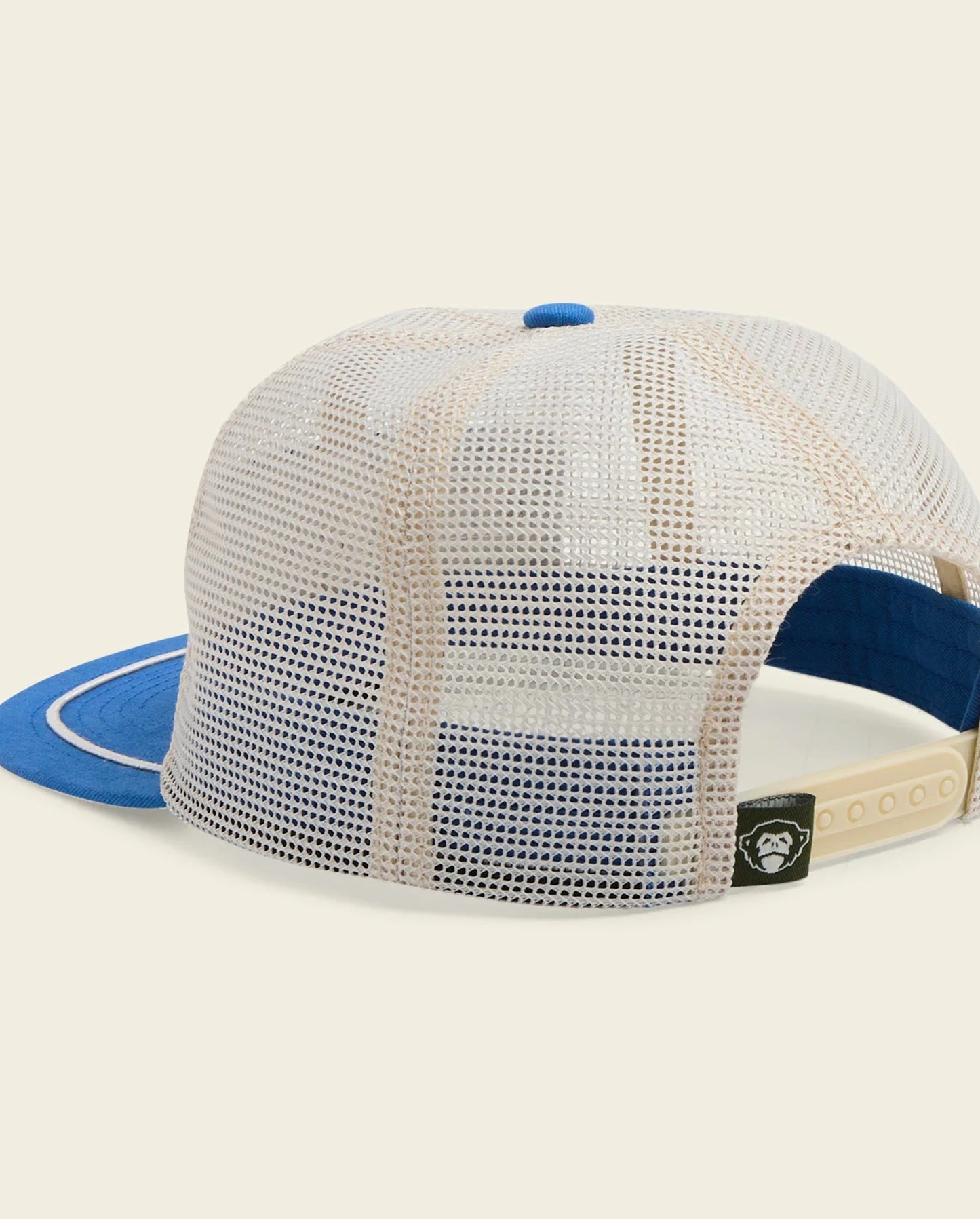 Mesh cap with blue visor and beige brim on a beige background