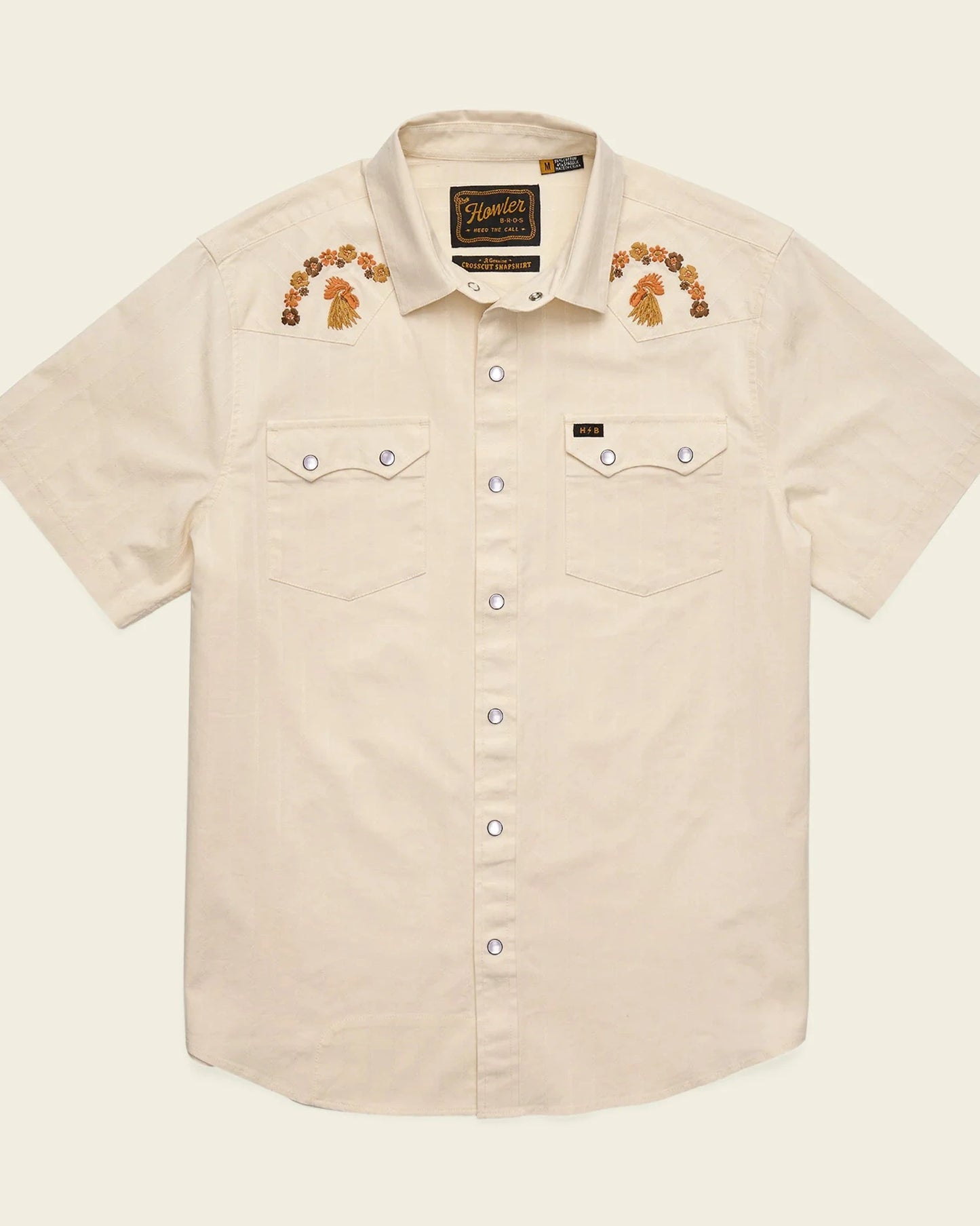Beige short-sleeve shirt with embroidered designs on a beige background