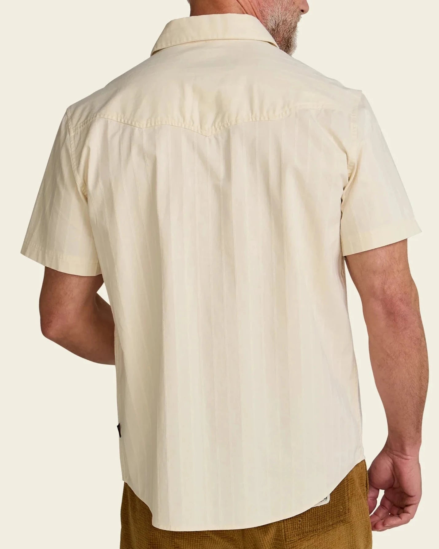 Man wearing a beige short-sleeve shirt on a plain background