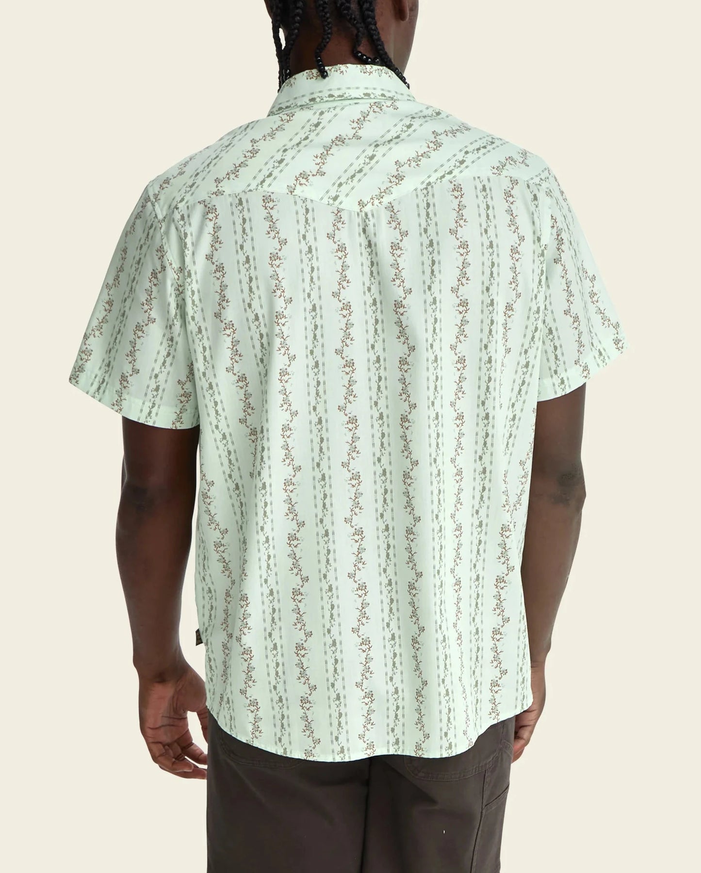 Person wearing a light green patterned shirt on a beige background