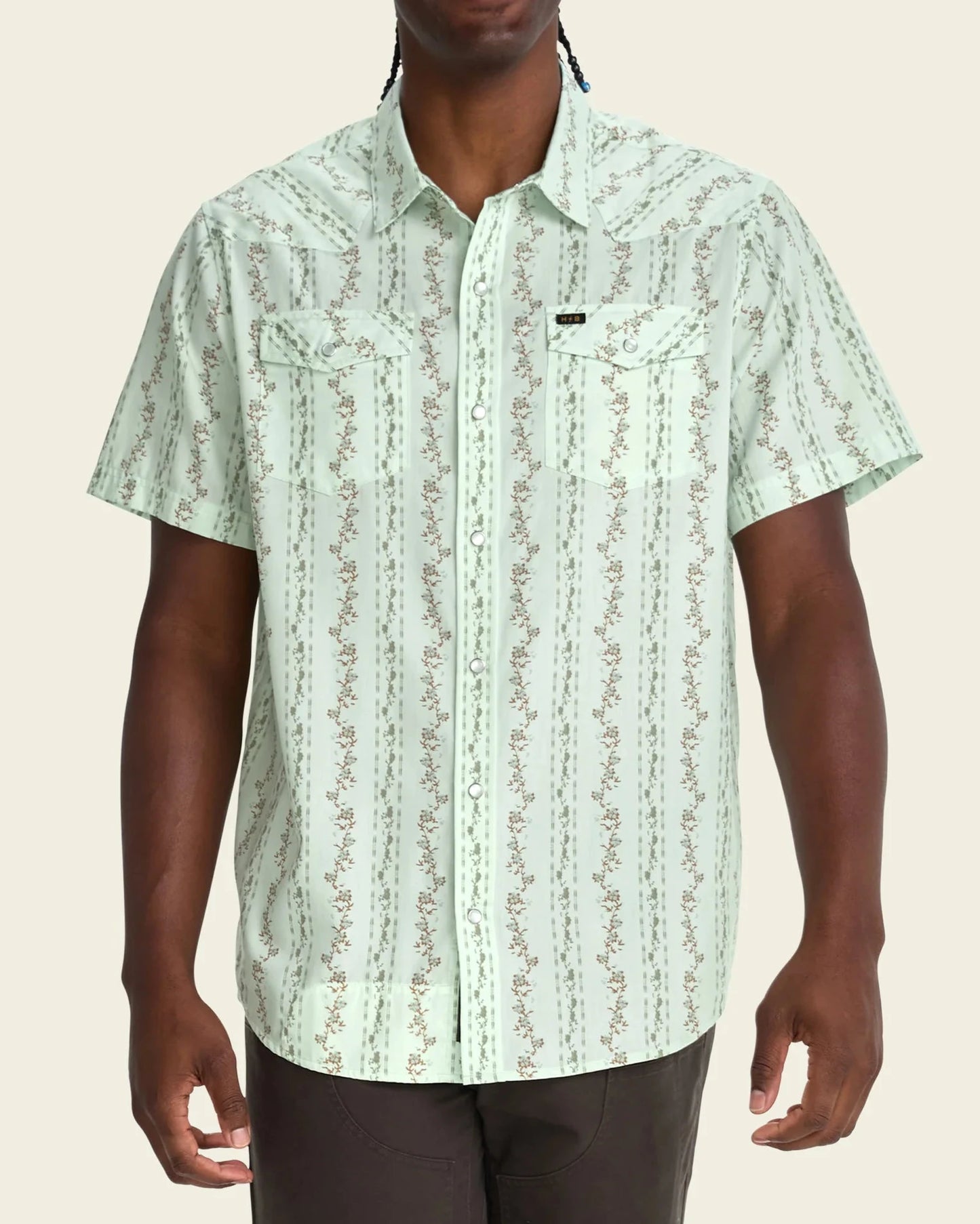 Man wearing a light green patterned shirt on a beige background