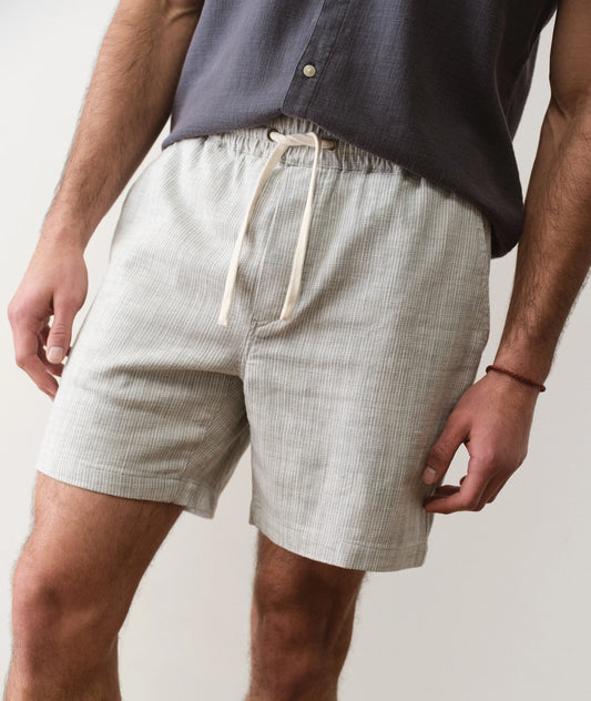 Person wearing light-colored shorts with a plain background
