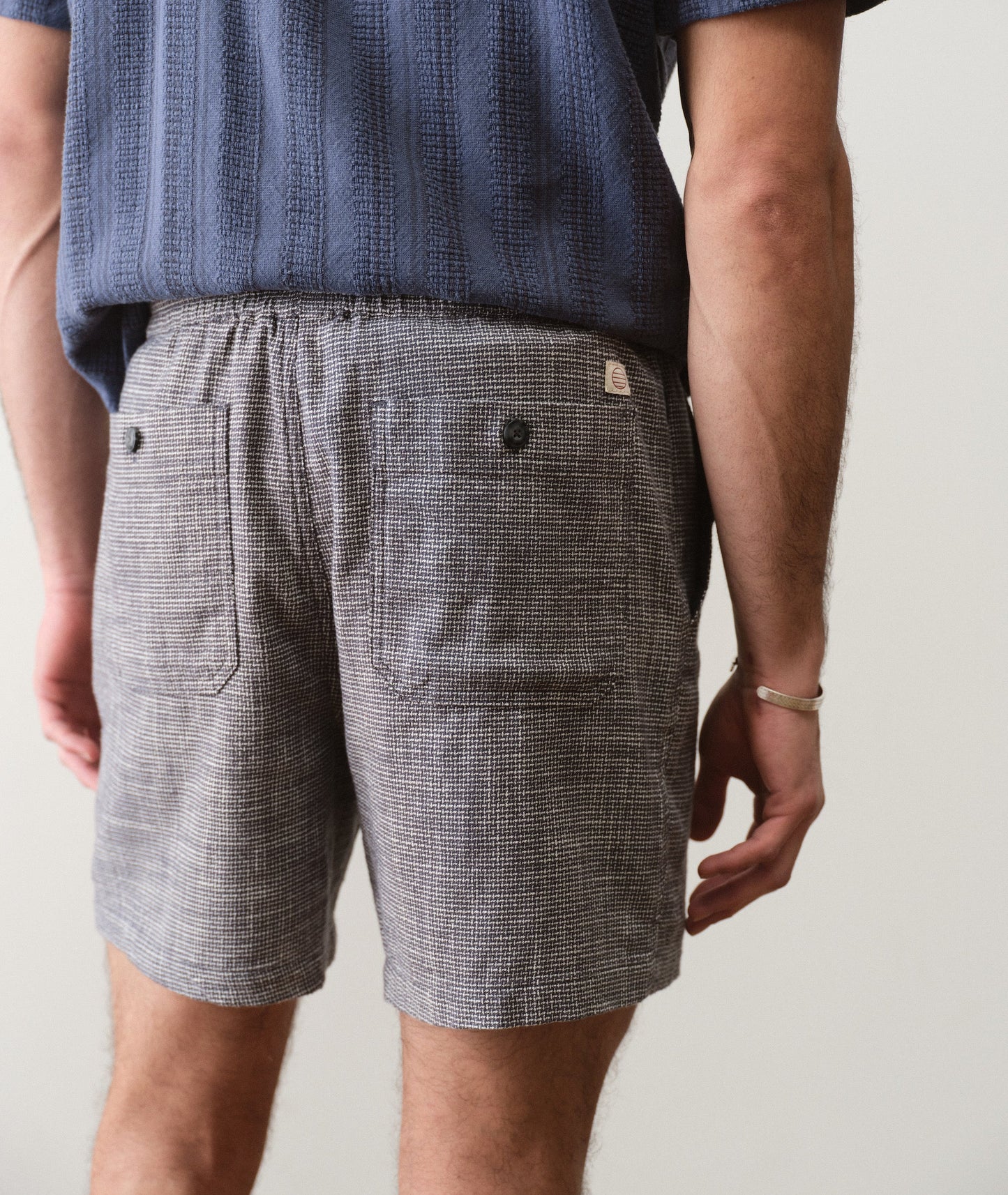 Person wearing gray checkered shorts with a plain background