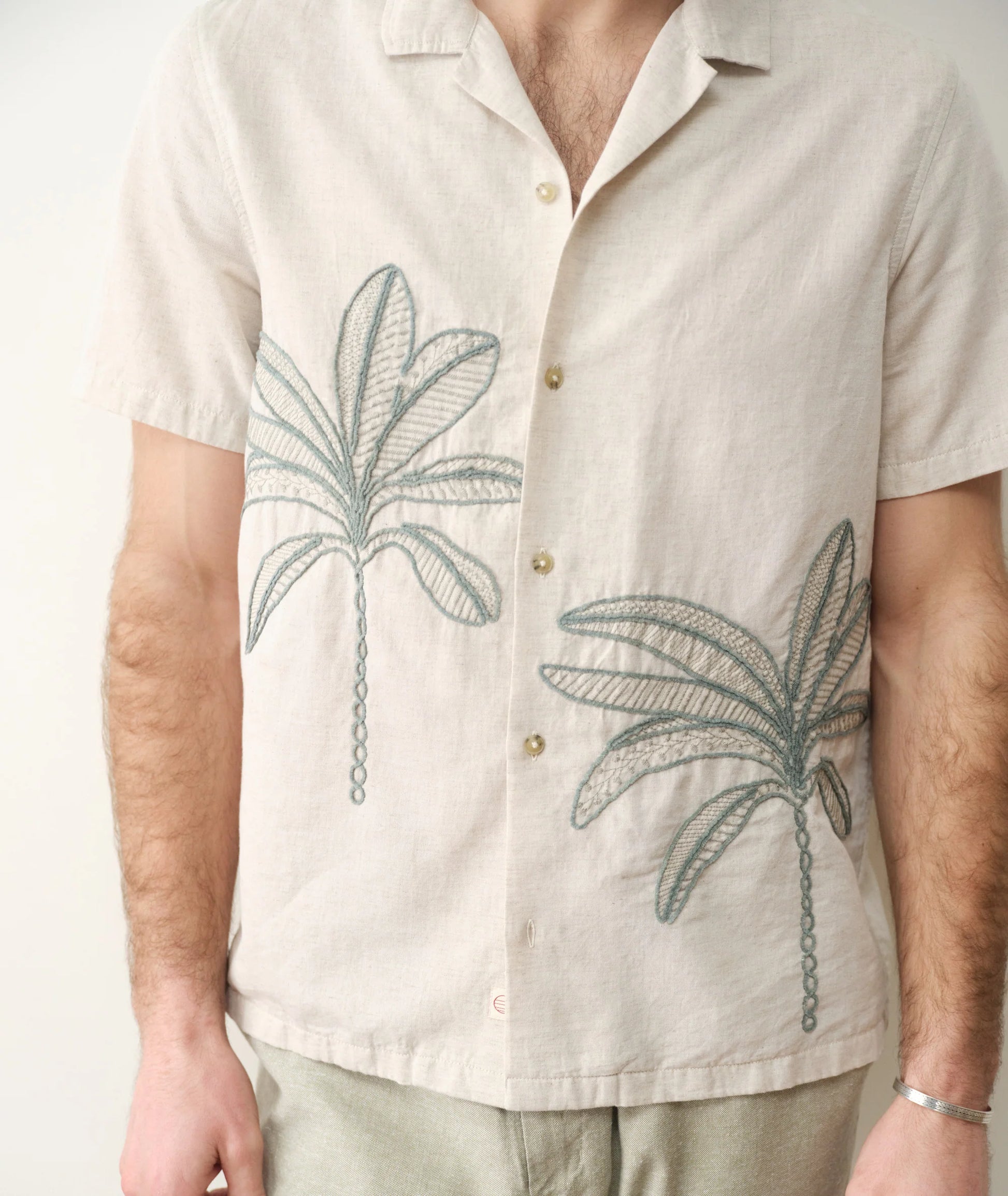 Beige shirt with palm tree designs worn by a person