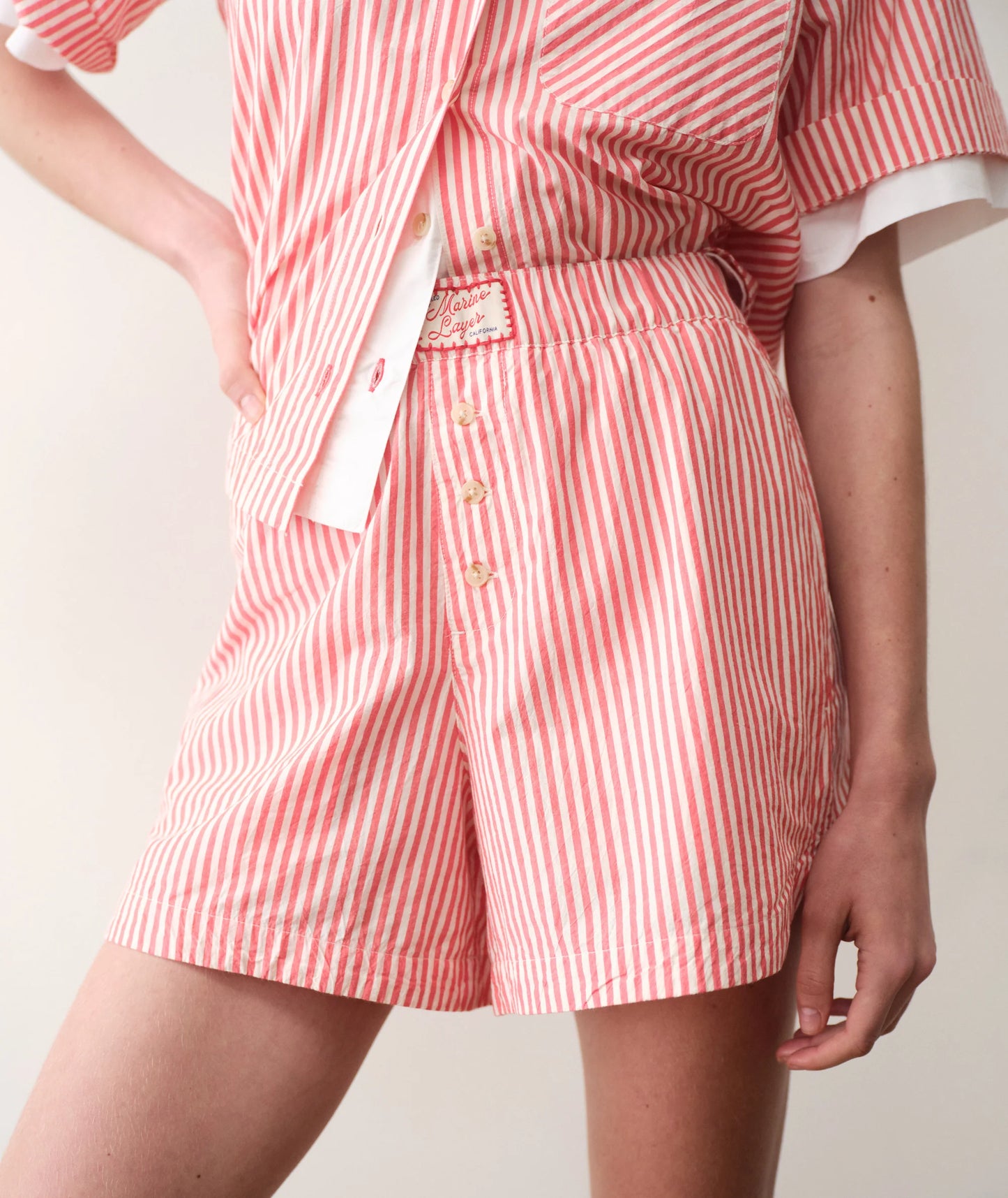 Person wearing a red and white striped shirt and shorts on a plain background