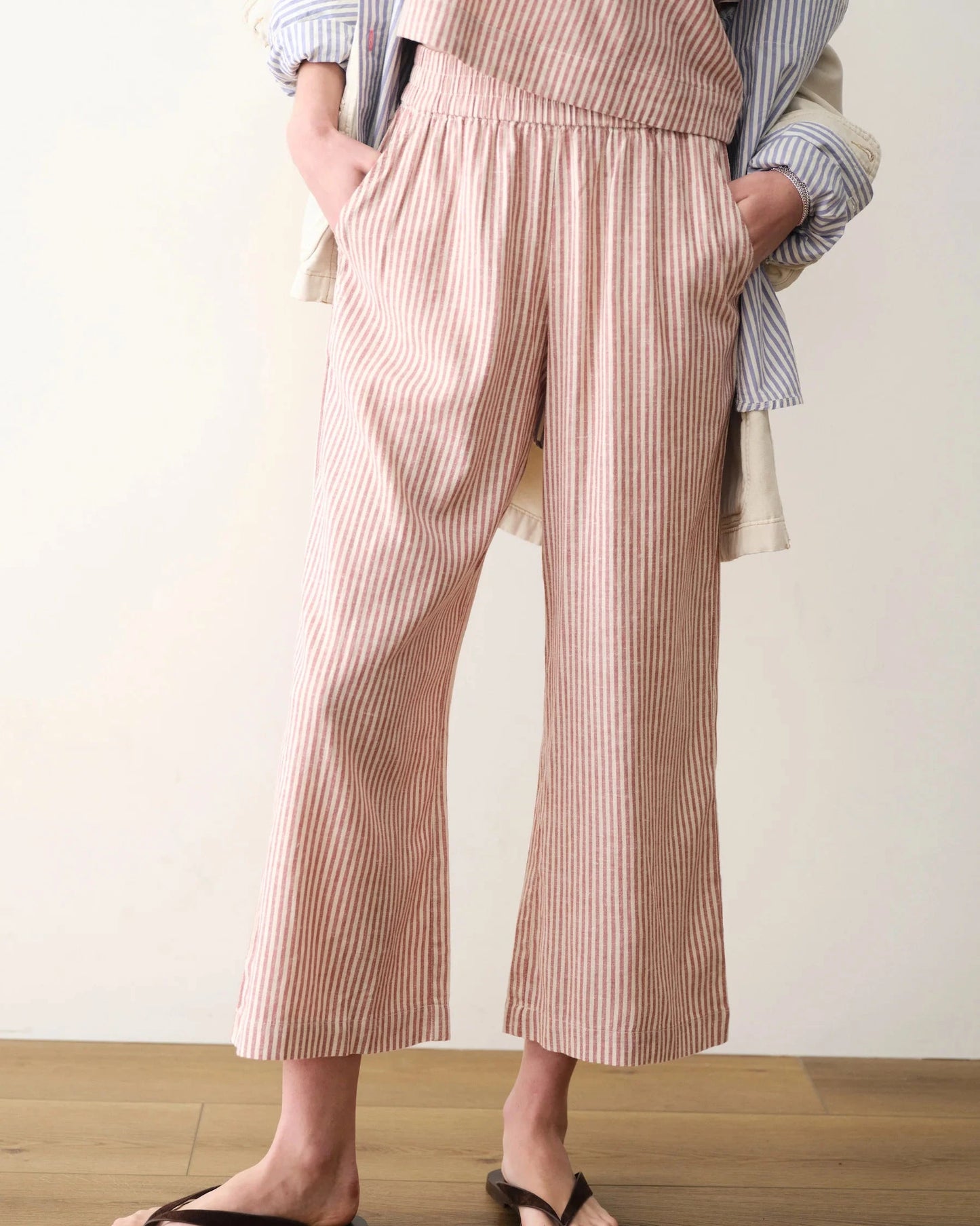 Person wearing a striped shirt and pink and white striped pants on a plain background