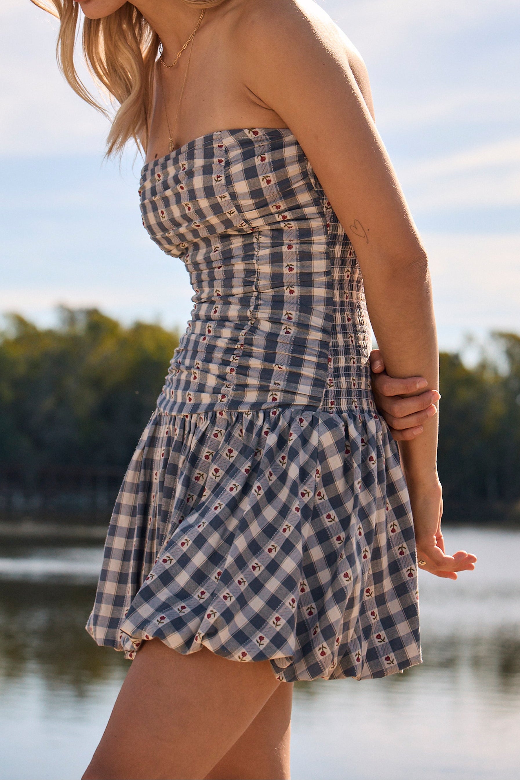 Woman in a strapless checkered dress and cowboy hat by a lake