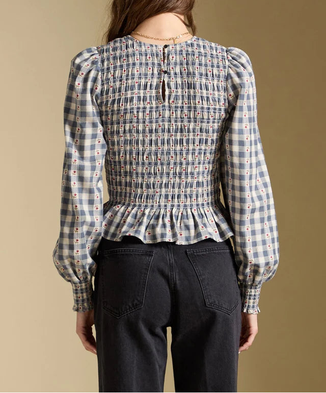 Person wearing a plaid blouse with a peplum waist on a beige background