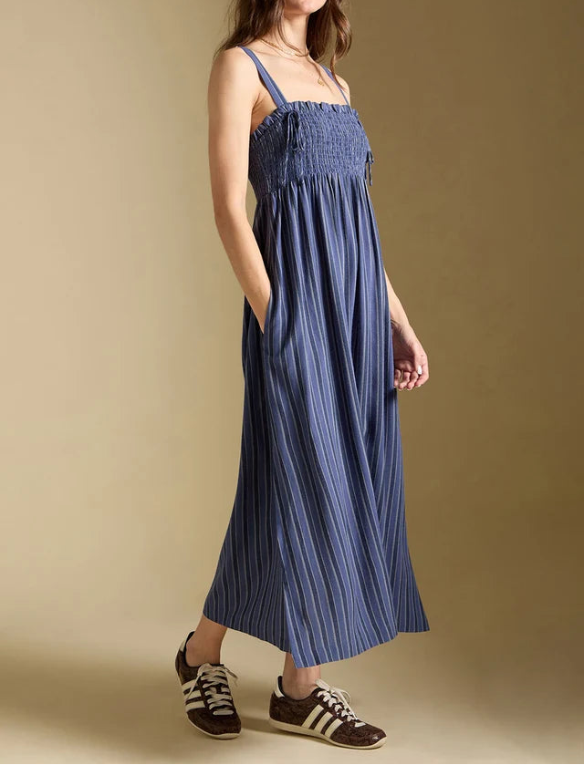 Woman wearing a blue dress and cap against a beige background