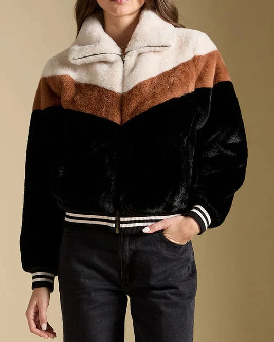 Woman wearing a black, brown, and white striped jacket against a beige background