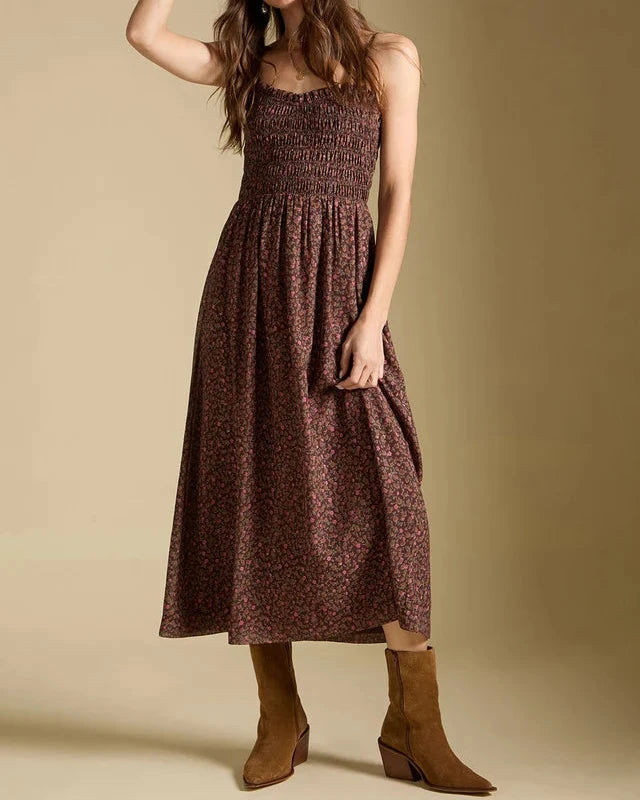 Woman wearing a brown patterned dress and white hat against a beige background