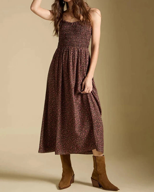 Woman wearing a brown patterned dress and white hat against a beige background