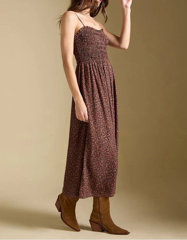 Woman wearing a patterned dress and hat against a beige background