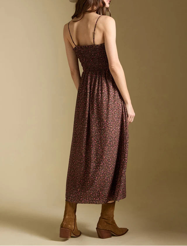 Woman wearing a brown floral dress and white hat against a beige background
