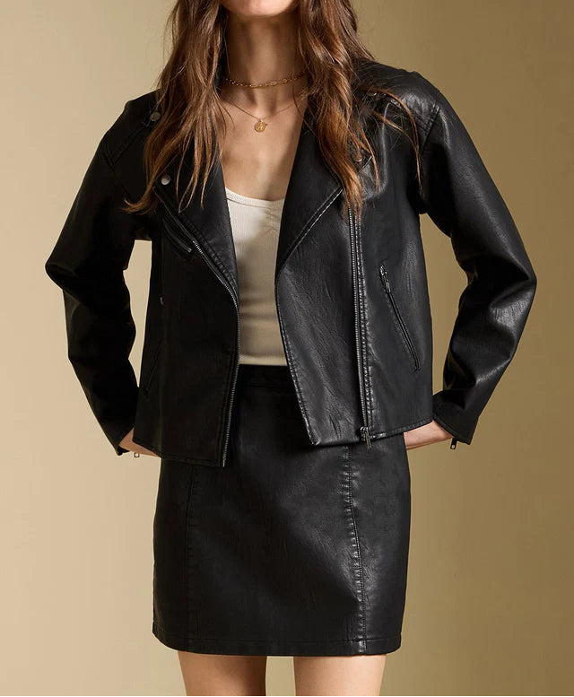 Woman wearing a black leather jacket and skirt against a beige background