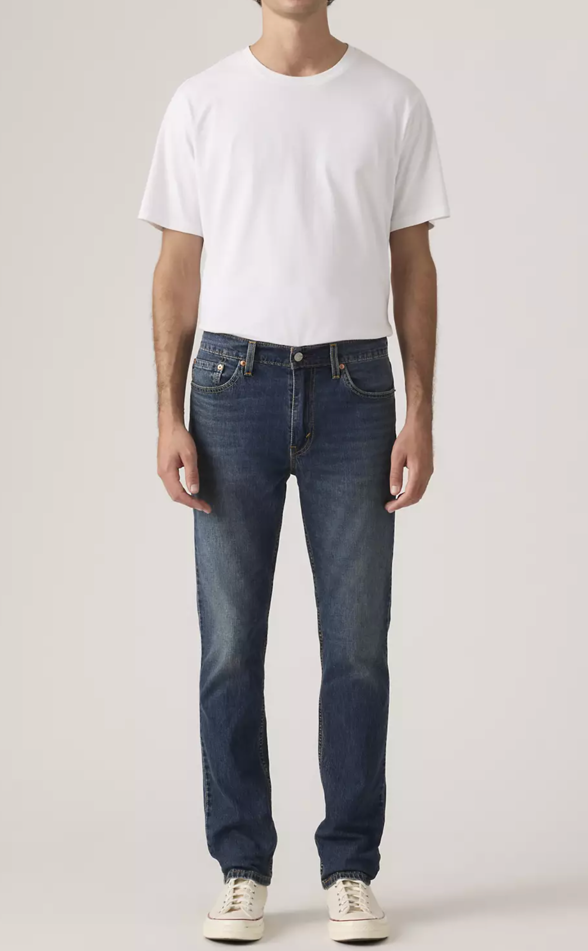 Person wearing a white t-shirt and blue jeans on a plain background