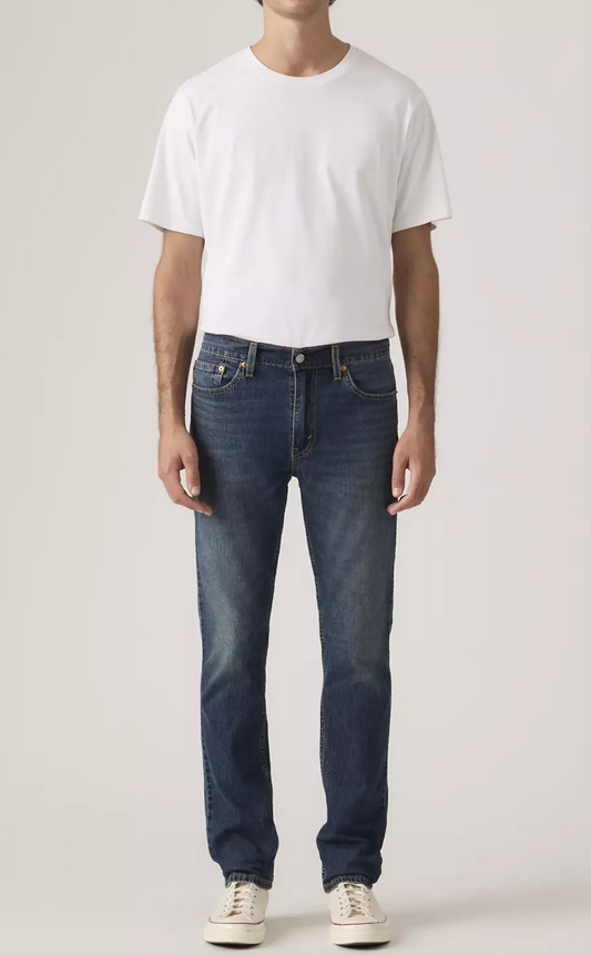 Person wearing a white t-shirt and blue jeans on a plain background