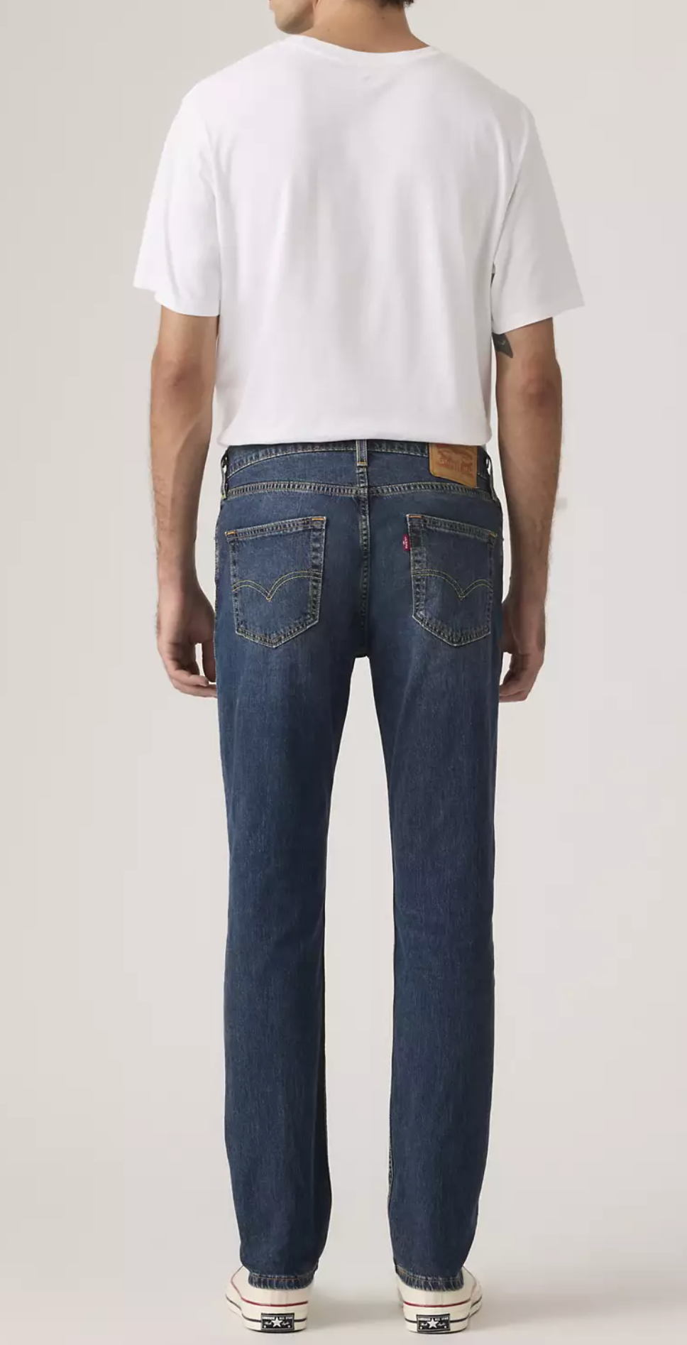 Person wearing a white t-shirt and blue jeans on a plain background