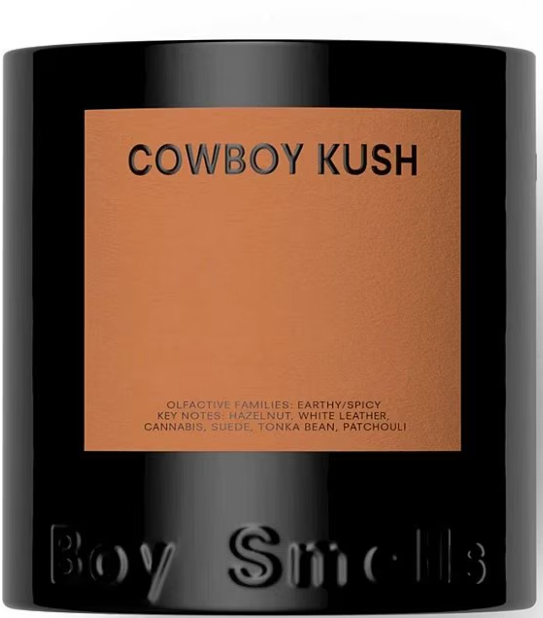 Candle with 'Cowboy Kush' label and 'Boy Smells' branding on a white background