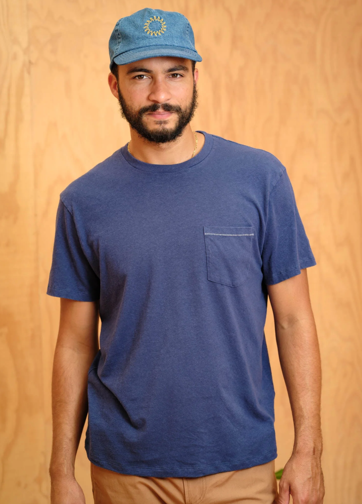 Man wearing a blue t-shirt and cap against a wooden background