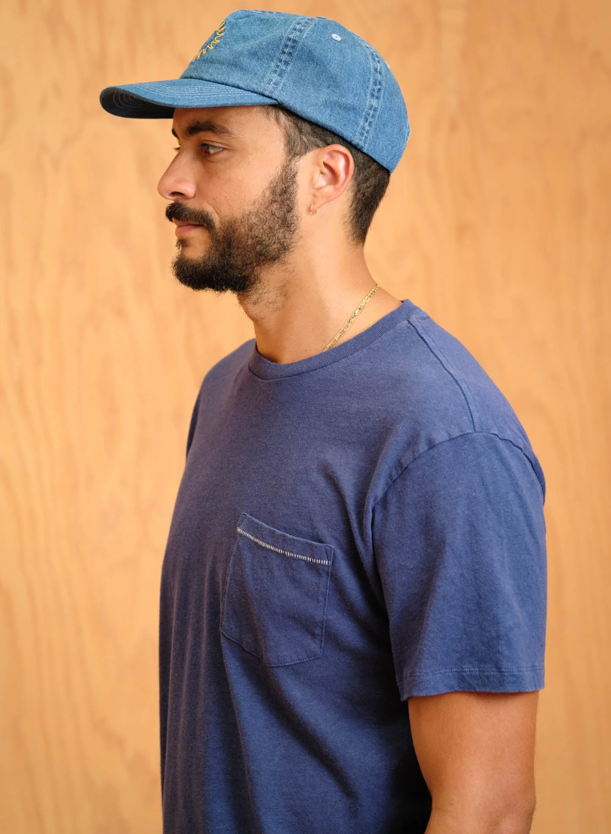 Man wearing a blue cap and t-shirt against a wooden background